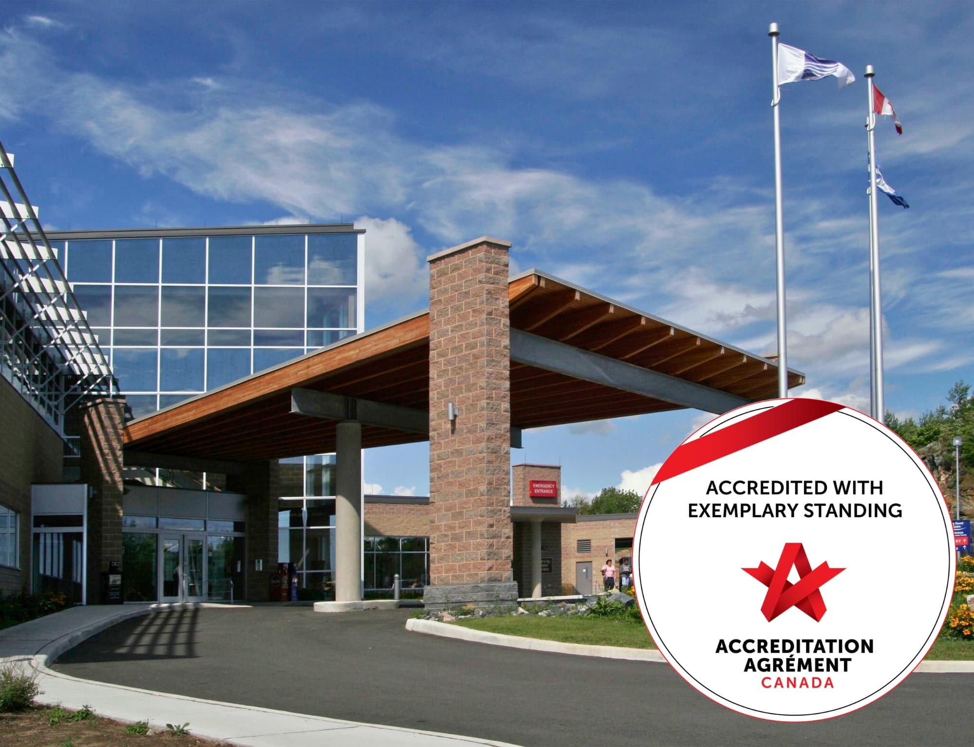 The West Parry Sound Health Centre main entrance viewed from a side angle on a bright sunny day. Superimposed in the right hand corner of the image is Accreditation Canada’s “ Accredited with Exemplary Standing” seal.